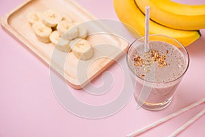 Fresh made banana smoothie in a glass on pink background