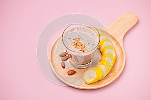 Fresh made banana smoothie in a glass on pink background