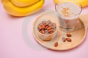 Fresh made banana smoothie in a glass on pink background