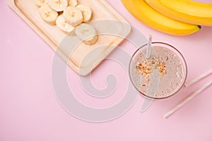 Fresh made banana smoothie in a glass on pink background