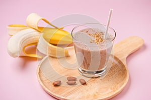 Fresh made banana smoothie in a glass on pink background