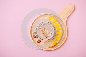 Fresh made banana smoothie in a glass on pink background