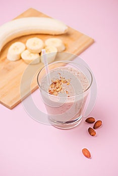 Fresh made banana smoothie in a glass on pink background