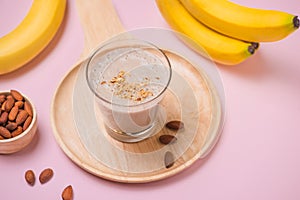 Fresh made banana smoothie in a glass on pink background