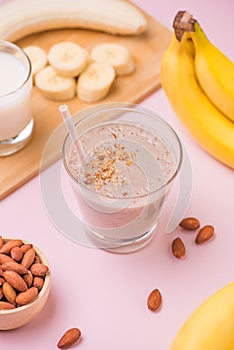 Fresh made banana smoothie in a glass on pink background