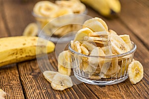 Portion of Dried Banana Chips on wooden background, selective focus