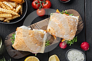 Fresh made Snack Sandwich with Fish Sticks, on wooden cutting board, on black wooden table background, top view flat lay