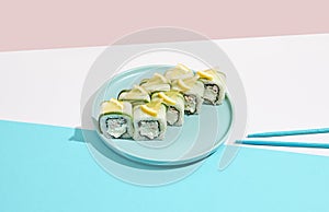Fresh maki roll with crab on coloured background. Sushi roll with crab and cheese inside, cucumber and lemon outside. Green Maki