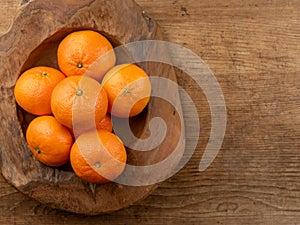 Fresh mandarin orange fruits in a wooden bowl