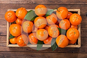 Fresh mandarin oranges fruit or tangerines with leaves in wooden