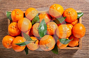 Fresh mandarin oranges fruit or tangerines with leaves in a wooden box