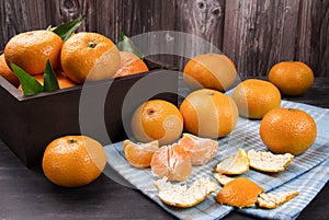 Fresh mandarin oranges fruit or tangerines with leaves in the wooden box