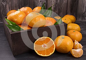 Fresh mandarin oranges fruit or tangerines with leaves in the wooden box