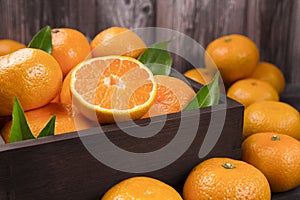 Fresh mandarin oranges fruit or tangerines with leaves in the wooden box