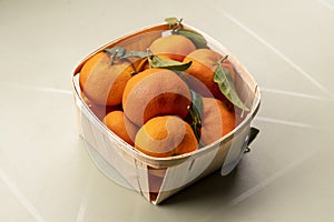 Fresh mandarin oranges fruit or tangerines with leaves in the wooden box. Ripe tangerines in a wooden basket. Healthy food concept