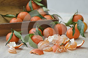 Fresh mandarin oranges fruit or tangerines with leaves on the wooden box on the table.