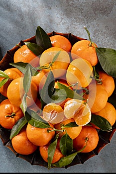 Fresh mandarin oranges fruit or tangerines with leaves in wooden box, top view