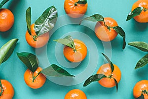 Fresh mandarins with leaves on turqoise background photo