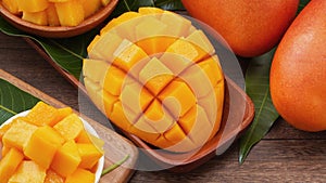 Fresh mango, beautiful chopped fruit with green leaves on dark wooden table background. Tropical fruit design concept. Flat lay.