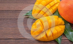 Fresh mango - beautiful chopped fruit with green leaves on dark wooden timber background. Tropical fruit design concept. Flat lay