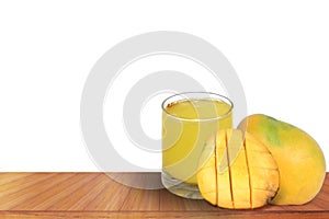 Fresh mango juice with ripe sliced mangoes on a wooden table with a white background