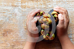 Fresh mangosteens in my hand on wood background, Ripe fruits a sweet tasty