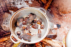 Fresh manioca roots boiling in hot water in traditional pot in african village kitchen