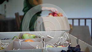 Fresh Market. Woman fills the box of Fruits and Vegetables with apples. Defocused