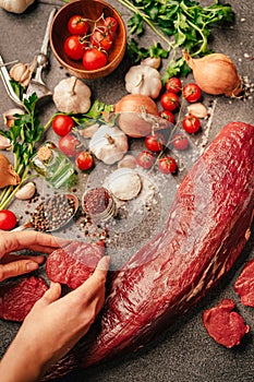 Fresh meat preparation and portioning.Whole uncut beef tenderloin.Raw meat seasoning.Hands portioning filet mignon steaks. Grass-