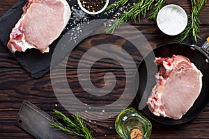 Fresh meat. Raw steak cutlet on a bone on a cast-iron frying pan, olive oil, spices and fresh rosemary on the kitchen table.