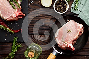 Fresh meat. Raw steak cutlet on a bone on a cast-iron frying pan, olive oil, spices and fresh rosemary on the kitchen table. Flat