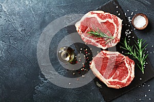 Fresh meat on slate black board top view. Raw beef steak and spices for cooking photo