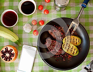 Fresh meat steak on a plate with vegetables and pomegranate stands