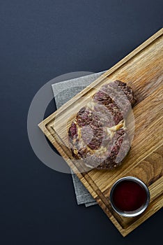 Fresh meat steak and seasonings on rustic wooden board over black background. Top view, flat lay, copy space banner.