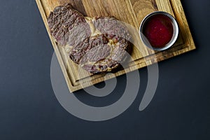 Fresh meat steak and seasonings on rustic wooden board over black background. Top view, flat lay, copy space banner.