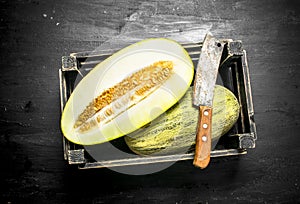 Fresh melon in a box with a hatchet.