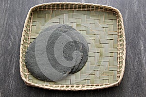 Fresh Mexican made blue corn tortillas ready to eat in taco on wooden table with woven base woven basket