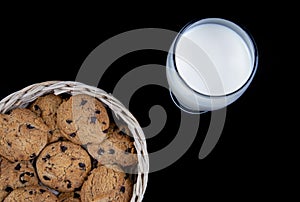 Fresh Milk and Chocolate chip cookies in a bamboo basket isolated on black background
