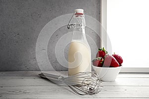 Fresh milk,cream bottle on window sill with strawberries