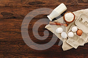 Fresh milk, eggs and flour over wooden background