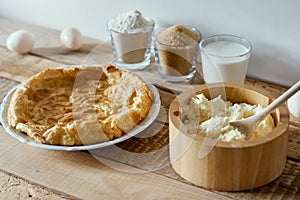 Fresh milk, flour, sugar, eggs and cake on a wooden table