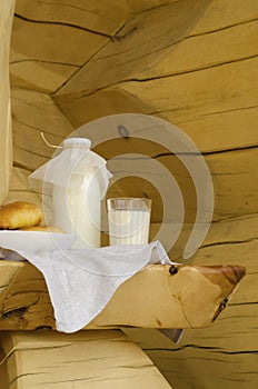 Fresh milk in a glass bottle and a glass, next to the pies on a wooden table. The concept of healthy organic products. Rusty style