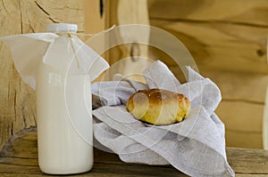 Fresh milk in a glass bottle and a glass, next to the pies on a wooden table. The concept of healthy organic products. Rusty style