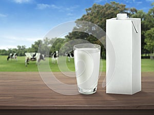 Fresh milk in glass on dark wooden tabletop and blurred landscape with cow on meadow. Healthy eating. Rustic style. Space for desi