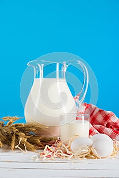 Fresh milk in glass and jug with eggs on wooden table top