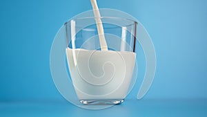 Fresh milk jet pouring transparent glass for healthy drinks vitamin nutrition slowmo isolated blue