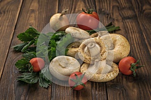 Fresh milk mushrooms, tomatoes and a bunch of parsley on a wooden background