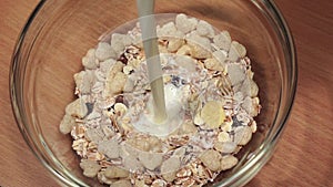 Fresh milk poured into plate with dry breakfast, slow motion