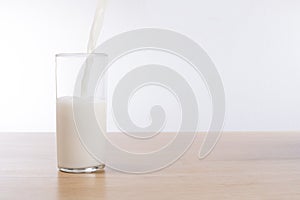 Fresh milk pouring into a glass on a bench top