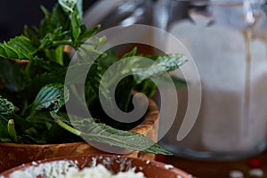 Fresh mint leaves in a bowl on wooden table, close-up, selective focus, shallow depth of field.